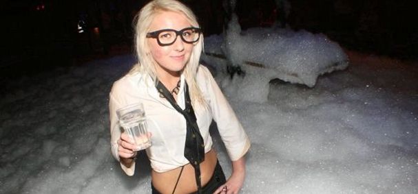 Nerd chic girl standing in foam at a party